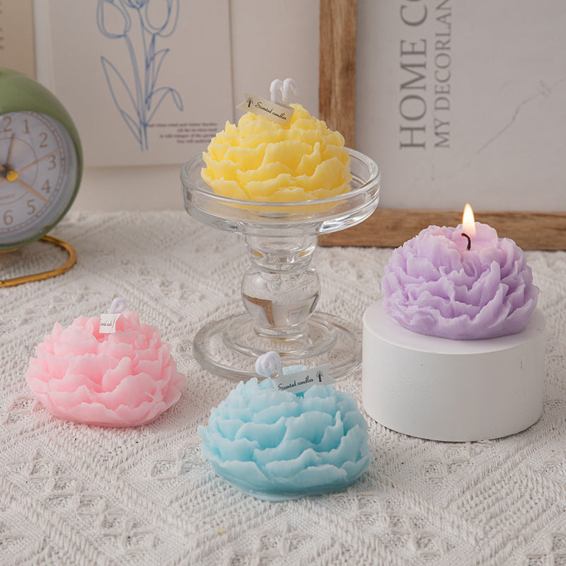 A handmade peony flower aromatherapy candle in a glass jar with a lit wick, showcasing soft floral design and warm glow.