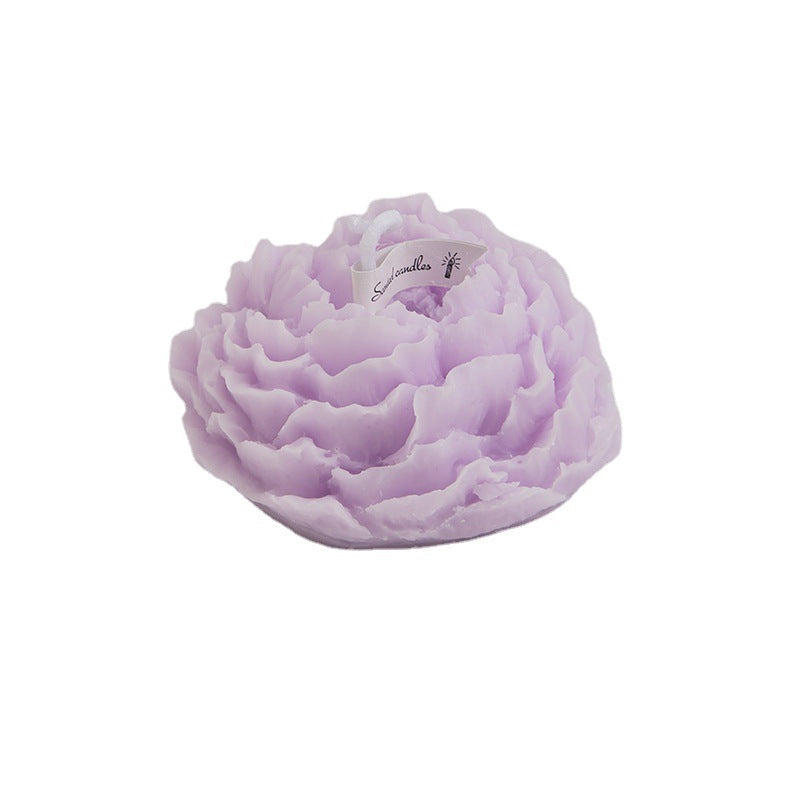 A handmade peony flower aromatherapy candle in a glass jar with a lit wick, showcasing soft floral design and warm glow.